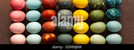 Brightly colored Easter eggs are arranged in a grid, displaying shades like pink, blue, green, and yellow. These eggs symbolize renewal and are often Stock Photo