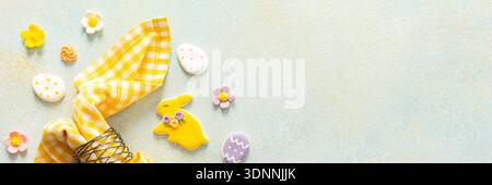 Festive decorations for Easter include a beautifully wrapped napkin holding a decorated egg, surrounded by colorful candies and floral accents in a pa Stock Photo