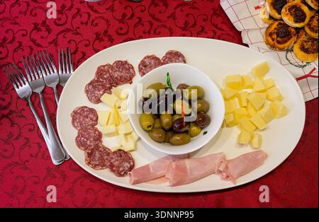 A white plate with a variety of meats and cheeses, including ham, salami, and cheese Stock Photo
