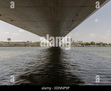 Bangkok, Thailand - Mar 02, 2025 - Beneath the massive concrete ribs of the Rama VIII Bridge, a dramatic architectural tunnel unfolds across the Chao Stock Photo