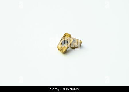 Two titanium nitride coated carbide inserts on a white background. Stock Photo