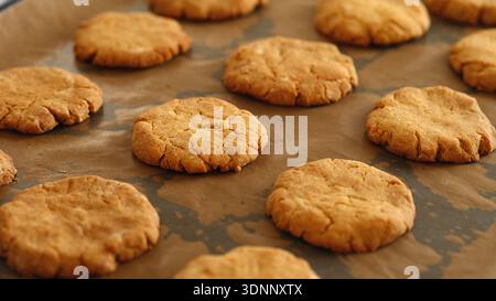 Freshly baked homemade gluten free cookies with a golden-brown cracked surface cooling on parchment paper. Close up. Stock Photo