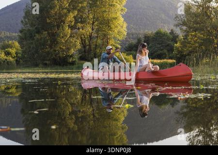 Two people kayak on a lake while enjoying nature and spending time together in a quiet outdoor setting. Stock Photo