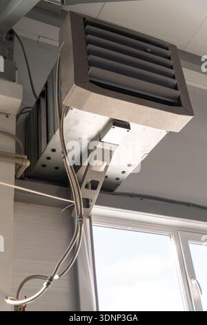 Industrial ventilation unit with air duct and louvered diffuser mounted under the ceiling. HVAC equipment in a factory or workshop for climate control Stock Photo