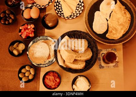 Traditional Turkish breakfast served on a table with eggs, bread, cheese, olives, spreads and tea. Rich food culture and slow morning lifestyle Stock Photo