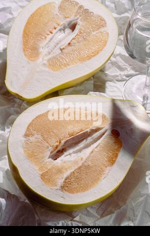 A visually striking image features a sliced pomelo arranged on crumpled paper, highlighting its juicy texture and vibrant colors, evoking a sense of f Stock Photo