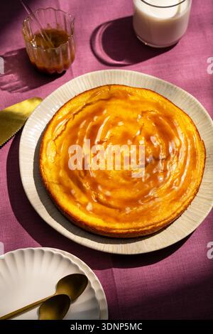 A homemade ricotta cheesecake sits elegantly on a white plate, showcasing its golden-brown crust and creamy texture. Perfectly set, this dessert captu Stock Photo