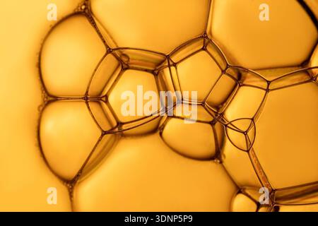 A stunning macro image showcasing the intricate structure of soap bubbles and foam. The golden hues create a vibrant and mesmerizing visual effect, ca Stock Photo
