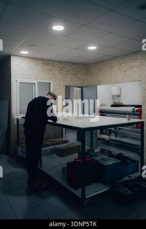 A professional technician is seen working in an automotive workshop, specializing in vehicle branding and customization. Tools and equipment are arran Stock Photo