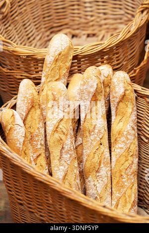 A collection of freshly baked artisanal baguettes is displayed in wicker baskets at a local bakery, highlighting the rustic charm and appealing textur Stock Photo
