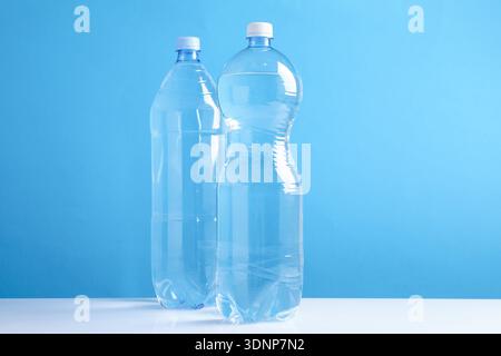 Bottles of fresh water on white table against light blue background Stock Photo