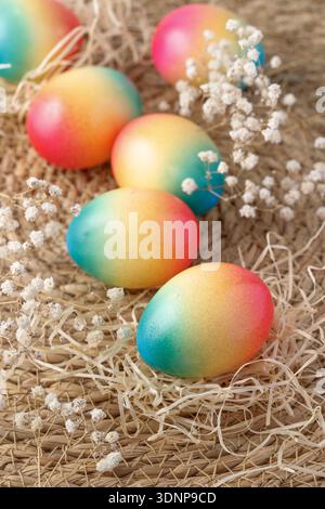 Easter painted colorful natural chicken eggs with dried hay and flowers scatered on rustic background. Happy easter festive card gift or decoration. Stock Photo