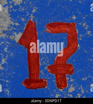 Parking number 17 with screen paint on concrete.red number 17 is written with a brush on concrete. Stock Photo