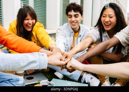 Young group of teenage students joining hands showing support and cooperation Stock Photo