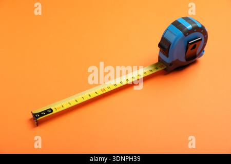 Blue measuring tape on orange background, closeup Stock Photo