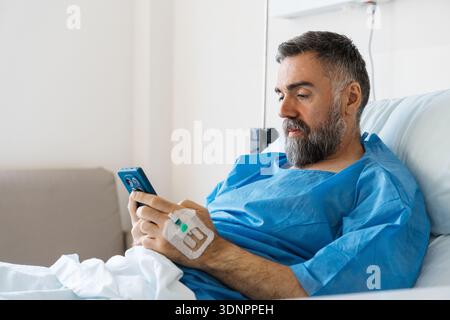 Patient using smartphone in hospital bed recovering Stock Photo