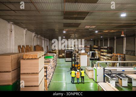 Workers walking in a large industrial lumberyard warehouse Stock Photo