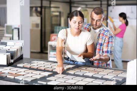 Interested couple browsing tile samples on display board in store Stock Photo