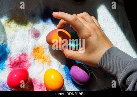Hand arranging dyed easter eggs on paper towel with colorful dye stains Stock Photo