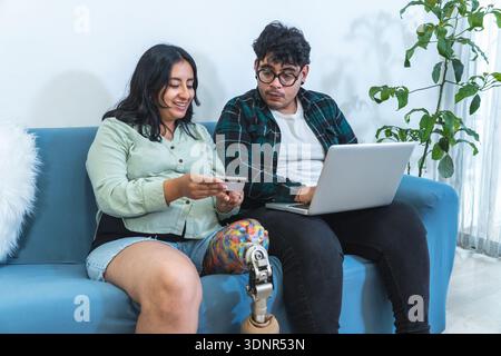 Couple using laptop and credit card for e-commerce on a sofa at home Stock Photo