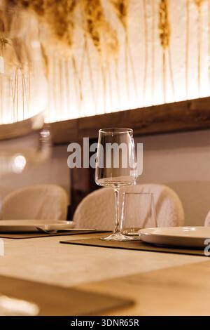 Wine glass on set restaurant table with warm candlelight and pampas decor Stock Photo