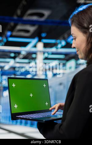 IT staff member in server hub using laptop to monitor energy ...