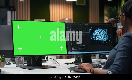 Green screen mockup computer used by programmer typing code, developing machine learning models to automate tasks. Developer writing programming language scripts on chroma key PC Stock Photo