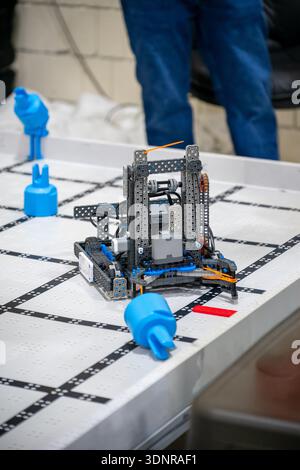 Students build and program a robot to navigate an obstacle course in a classroom during a science club meeting Stock Photo