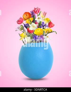 Easter card with spring flowers in broken eggshell on pink background Stock Photo