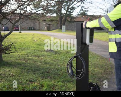 Technician installing a new ev charging station, promoting sustainable transportation solutions Stock Photo