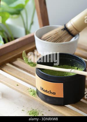Green tea matcha powder spilling from a measuring scoop on a wooden tray Stock Photo
