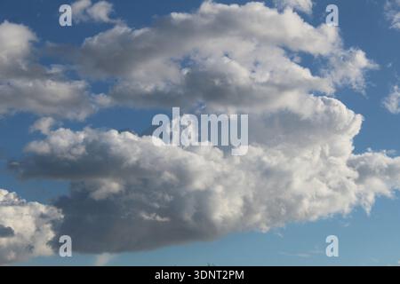 white fluffy clouds in a light blue sky. Clear weather. Stock Photo