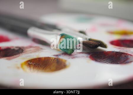 Colorful paints and brushes on a mixing palette Stock Photo