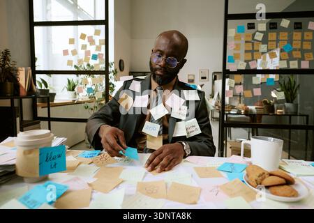 Black Man Organizing Sticky Notes during Busy Business Planning Stock Photo