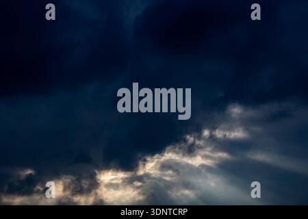 Dramatic sunbeams breaking through dark storm clouds Stock Photo
