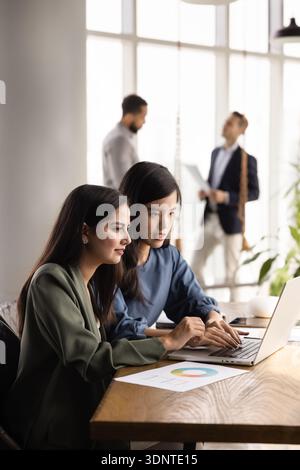 Two focused multiethnic analysts doing Internet marketing research Stock Photo