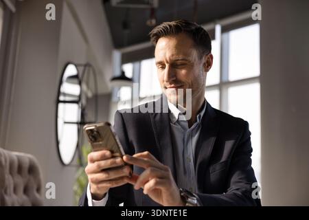 Positive handsome Hispanic CEO man using online business application Stock Photo