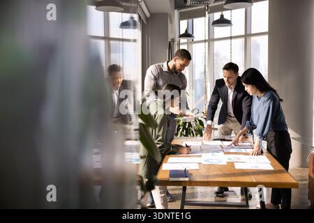 Four diverse business analysts discussing paper reports at meeting table Stock Photo