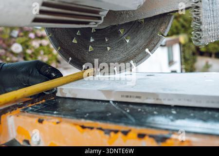 Diamond cutting disc slicing ceramic tile on a wet tile cutter. Construction and renovation.Professional tile cutting equipment preparing ceramic Stock Photo