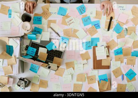 Young Adult Woman Organizing Sticky Notes on Desk While Working Stock Photo