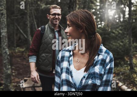 Smile, couple and hiking for travel in forest for adventure, trekking trip or bonding on holiday. Happy, people and walking in woods to explore nature Stock Photo