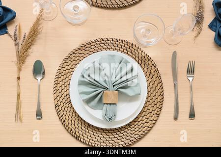 Elegant table setting with wicker mat, folded napkin and cutlery Stock Photo