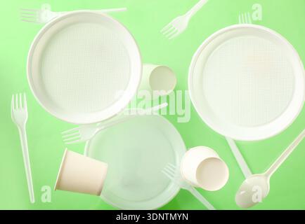 White plastic tableware levitating on green background Stock Photo