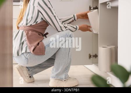 Housewife taking roll of paper towels from drawer in kitchen Stock Photo