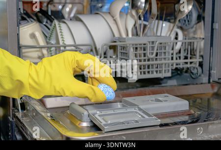 Putting detergent tablet into dishwasher for kitchen hygiene Stock Photo