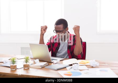 Angry black businessman in office, work with laptop Stock Photo