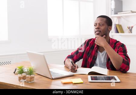 African american businessman using laptop and making notes Stock Photo