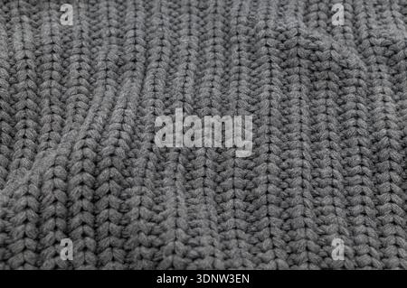 Close-up texture of dark grey knitted wool fabric. Soft knitwear material with vertical ribbing pattern. Cozy winter textile background. Stock Photo