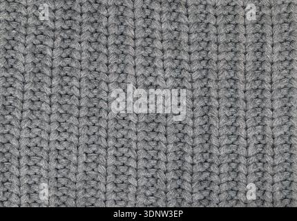 Close-up texture of dark grey knitted wool fabric. Soft knitwear material with vertical ribbing pattern. Cozy winter textile background. Stock Photo