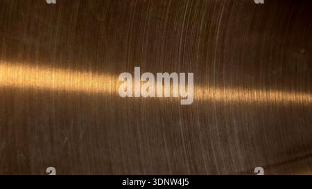Brushed dark bronze metal texture with light reflection. This warm industrial surface features circular hairline scratches and metallic glow perfect f Stock Photo